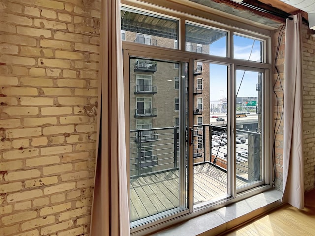 entryway with plenty of natural light, brick wall, wood finished floors, and a view of city