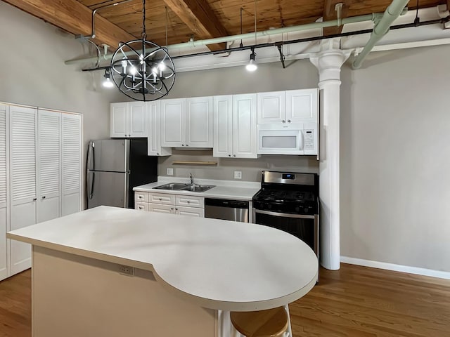 kitchen with appliances with stainless steel finishes, a sink, white cabinets, light countertops, and a towering ceiling