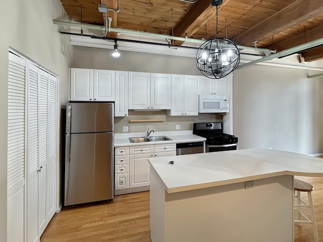 kitchen featuring stainless steel appliances, a sink, white cabinetry, light countertops, and light wood-type flooring