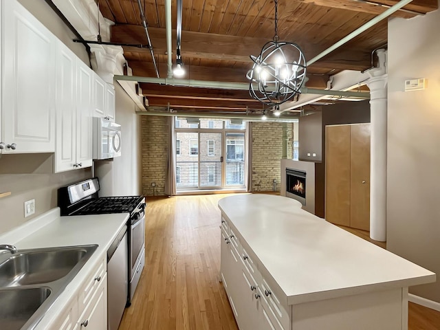 kitchen with wooden ceiling, a sink, stainless steel appliances, light wood finished floors, and a kitchen island