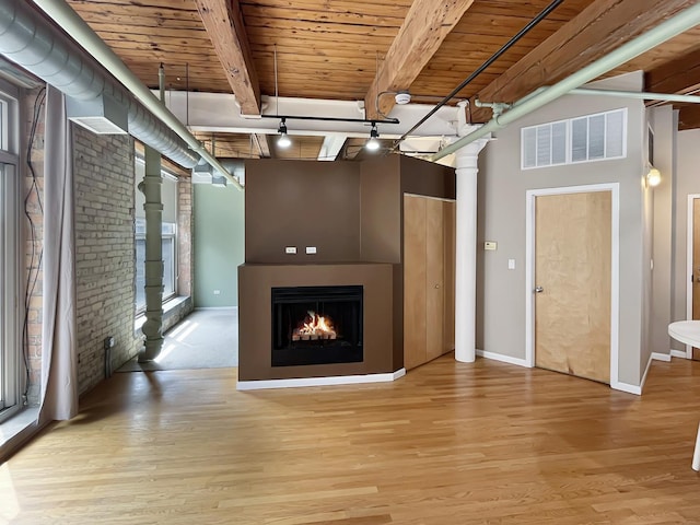 unfurnished living room with wooden ceiling, light wood-type flooring, a lit fireplace, beamed ceiling, and baseboards
