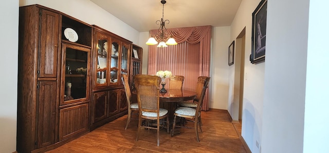 dining room with a chandelier, wood finished floors, and baseboards
