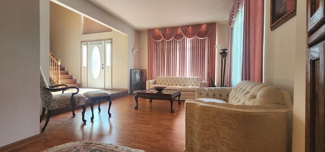 living area with wood finished floors, stairway, and baseboards