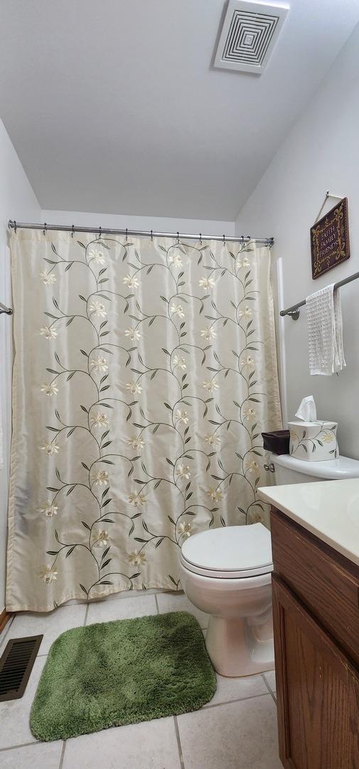full bathroom featuring vanity, toilet, tile patterned floors, a shower with shower curtain, and lofted ceiling