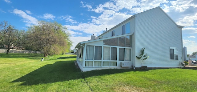 rear view of property with a lawn, a chimney, and a sunroom
