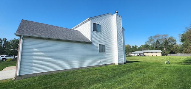 view of side of home featuring a lawn, a shingled roof, and a chimney