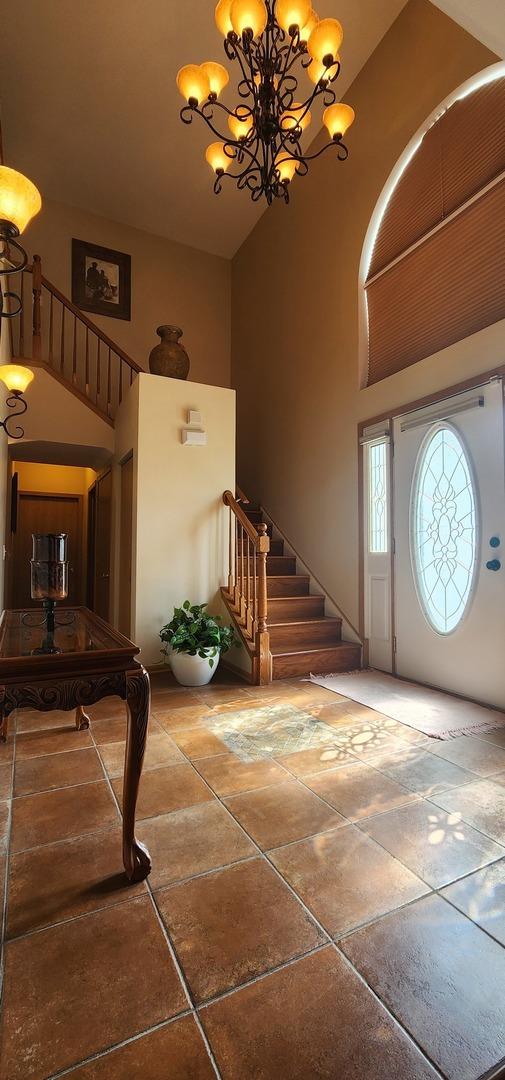 foyer with a high ceiling, stairs, and a chandelier