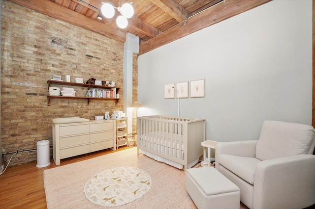 2435 N Sheffield Ave Unit 10, Chicago, IL 60614 - bedroom featuring wood ceiling, brick wall, light wood-style flooring, beam ceiling, and a crib