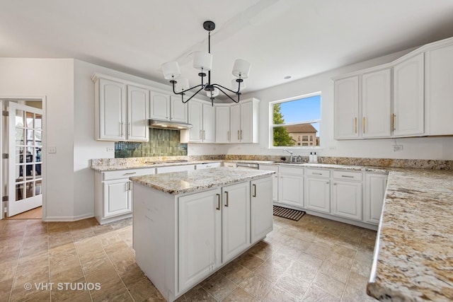 635 Mansfield Way, Oswego, IL 60543 - kitchen featuring under cabinet range hood, white cabinetry, a chandelier, light stone counters, and a kitchen island