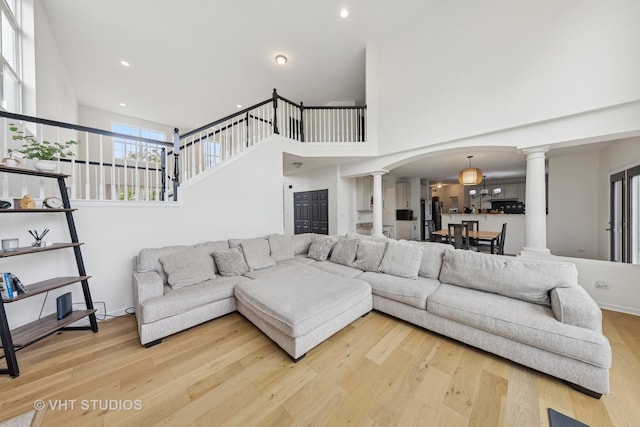 635 Mansfield Way, Oswego, IL 60543 - living room with decorative columns, light wood-style floors, arched walkways, a towering ceiling, and recessed lighting