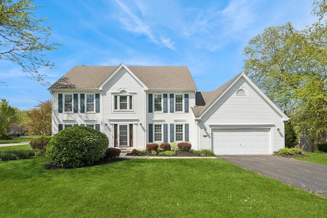 colonial inspired home with driveway, a garage, and a front lawn