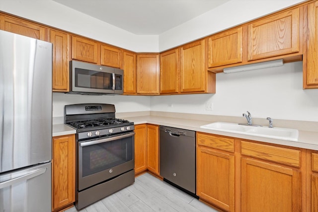 11046 Quail Dr, Mokena, IL 60448 - kitchen featuring appliances with stainless steel finishes, a sink, light countertops, brown cabinetry, and light wood-style floors