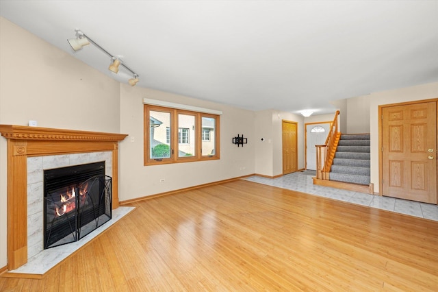 11046 Quail Dr, Mokena, IL 60448 - unfurnished living room featuring a tile fireplace, stairway, baseboards, wood finished floors, and track lighting