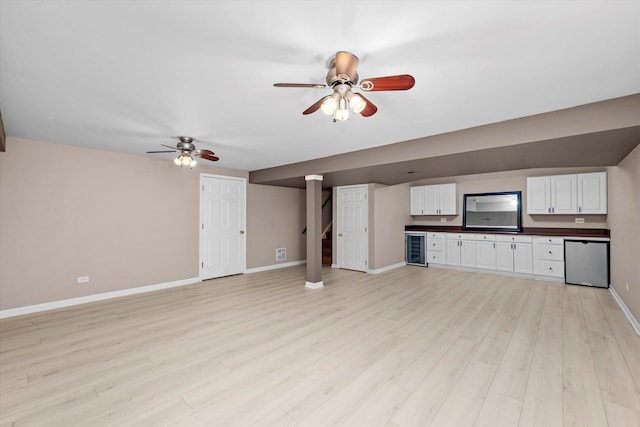 11046 Quail Dr, Mokena, IL 60448 - unfurnished living room featuring a ceiling fan, baseboards, light wood-type flooring, wine cooler, and bar