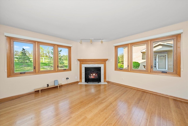11046 Quail Dr, Mokena, IL 60448 - unfurnished living room with light wood finished floors, a tile fireplace, baseboards, and rail lighting