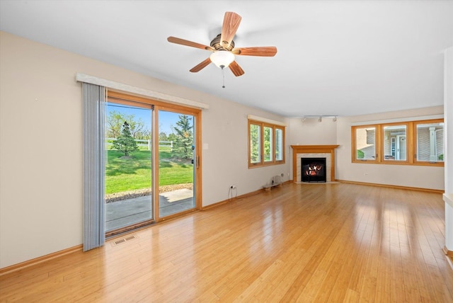 11046 Quail Dr, Mokena, IL 60448 - unfurnished living room featuring light wood-style flooring, a fireplace with flush hearth, a ceiling fan, and baseboards