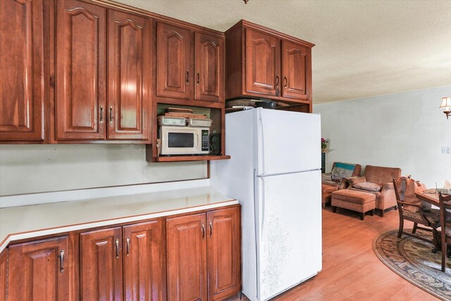 7 Birch Ln, Villa Grove, IL 61956 - kitchen with white appliances, light wood-type flooring, light countertops, a textured ceiling, and open floor plan