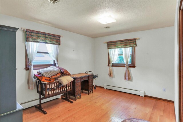 7 Birch Ln, Villa Grove, IL 61956 - living area featuring baseboard heating, light wood-style floors, a textured ceiling, and baseboards