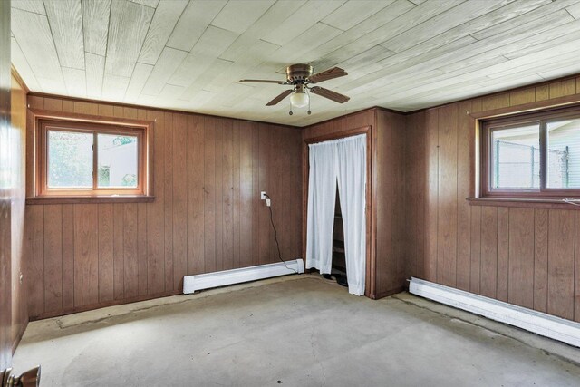 7 Birch Ln, Villa Grove, IL 61956 - unfurnished room featuring a baseboard heating unit, plenty of natural light, unfinished concrete floors, a ceiling fan, and wood walls