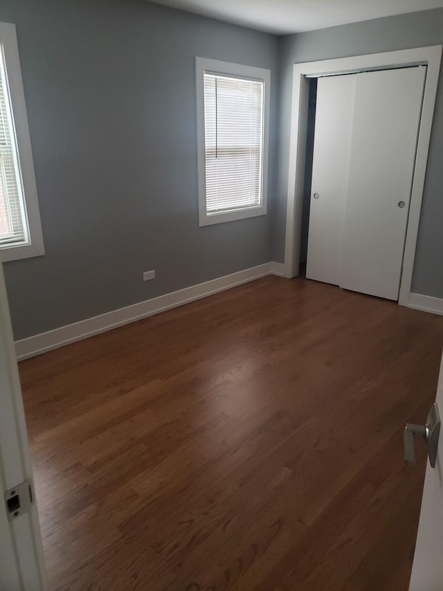 unfurnished bedroom with wood finished floors, a closet, and baseboards