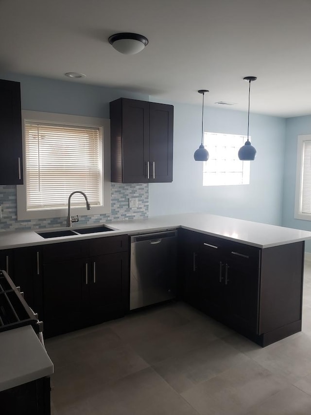 kitchen featuring stainless steel dishwasher, a sink, a peninsula, tasteful backsplash, and light countertops