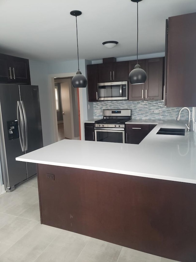 kitchen with appliances with stainless steel finishes, a sink, light countertops, and backsplash