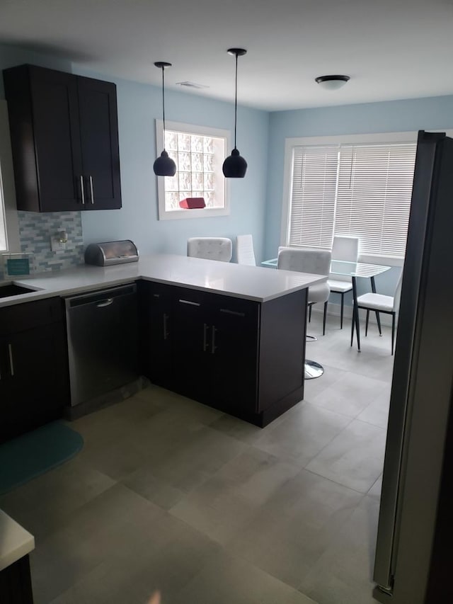 kitchen with dishwashing machine, dark cabinets, light countertops, and freestanding refrigerator