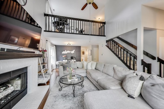 405 W Ivy Ln Unit 4A, Arlington Heights, IL 60004 - living room featuring ceiling fan, wood finished floors, a towering ceiling, stairs, and a brick fireplace