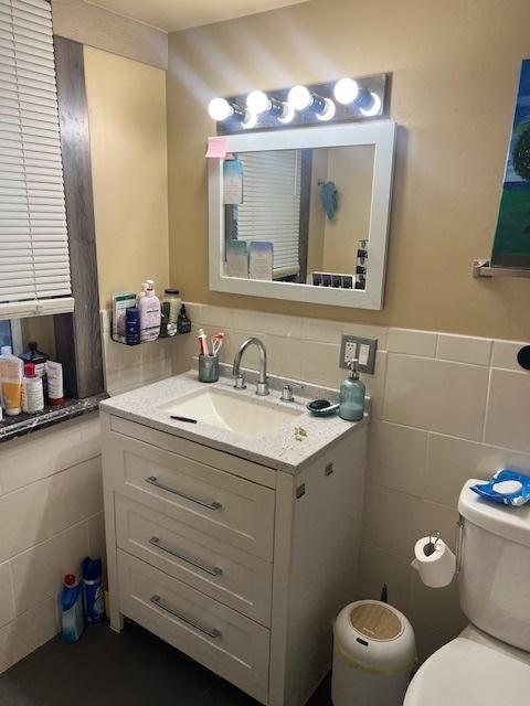 1428 S St Louis Ave, Chicago, IL 60623 - half bathroom featuring tile walls, toilet, vanity, and a wainscoted wall