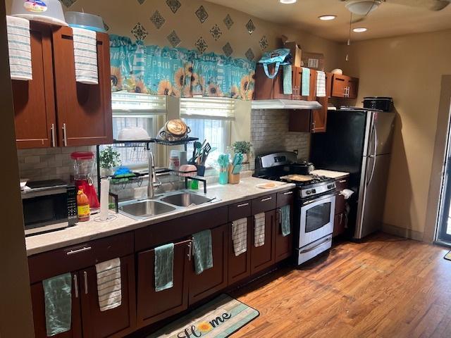 1428 S St Louis Ave, Chicago, IL 60623 - kitchen with gas stove, a sink, tasteful backsplash, light countertops, and light wood finished floors