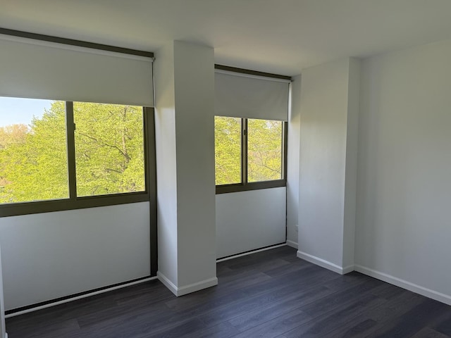 unfurnished room with dark wood-type flooring and baseboards