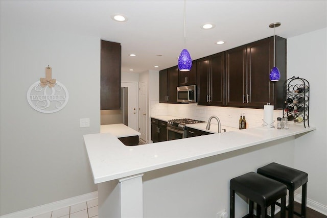 1608 W Ethans Glen Dr, Palatine, IL 60067 - kitchen with stainless steel appliances, backsplash, light countertops, dark brown cabinetry, and baseboards
