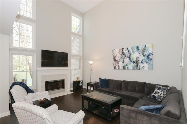 1608 W Ethans Glen Dr, Palatine, IL 60067 - living room featuring a towering ceiling, dark wood-type flooring, a tile fireplace, healthy amount of natural light, and baseboards