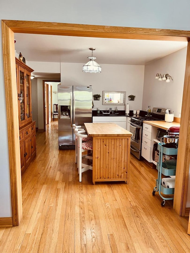 1723 N Richmond St, Chicago, IL 60647 - kitchen featuring stainless steel appliances, butcher block counters, light wood-style flooring, a center island, and glass insert cabinets