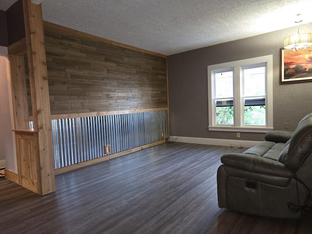 101 4th St, Fisher, IL 61843 - sitting room featuring wood walls, dark wood-type flooring, baseboards, a textured ceiling, and a textured wall