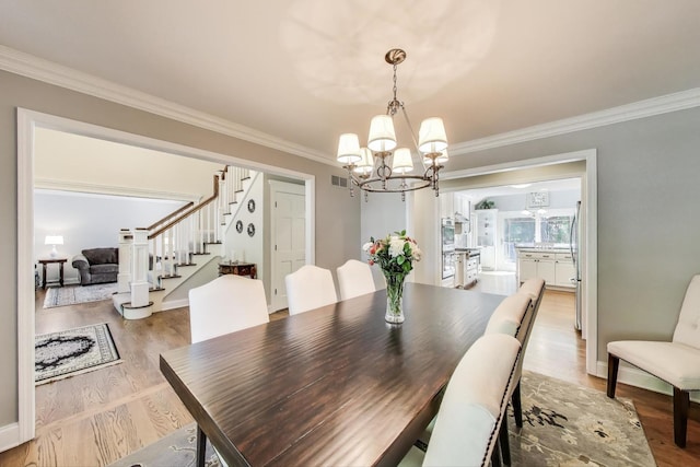 2041 Chatham Dr, Wheaton, IL 60189 - dining space featuring stairway, a chandelier, ornamental molding, and light wood-style floors
