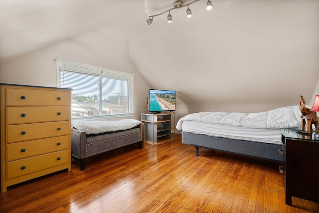 bedroom with light wood finished floors and vaulted ceiling