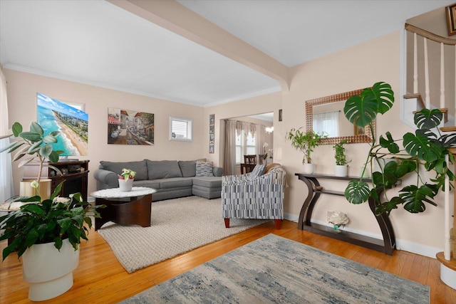 living area with ornamental molding, wood finished floors, baseboards, and stairway