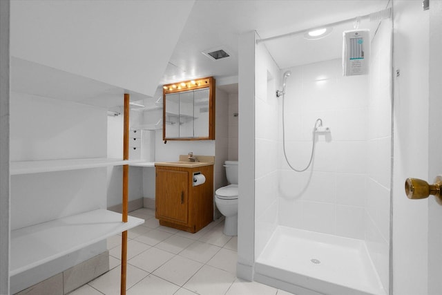 bathroom featuring toilet, a tile shower, vanity, and tile patterned flooring