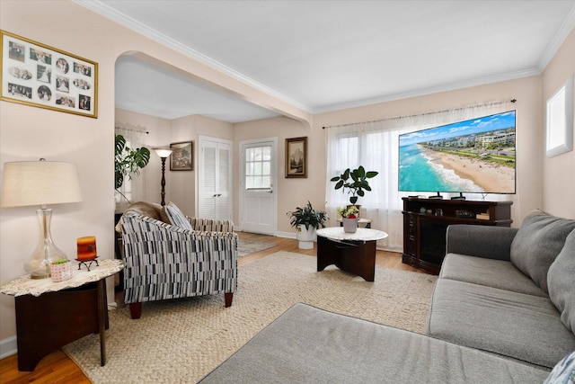 living room with wood finished floors, crown molding, and baseboards