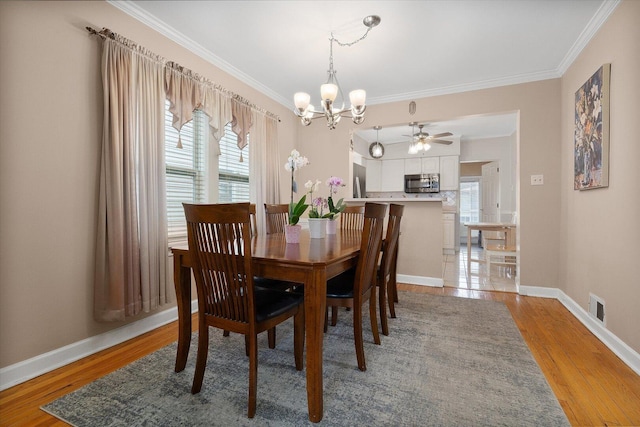dining room with crown molding, a chandelier, plenty of natural light, light wood-type flooring, and baseboards