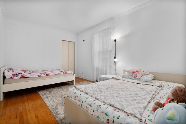 bedroom featuring crown molding, hardwood / wood-style floors, a closet, and baseboards
