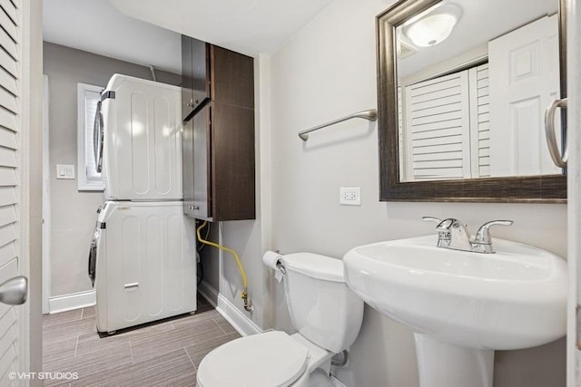 36 Chestnut Rd, Northbrook, IL 60062 - half bathroom featuring stacked washer and clothes dryer, baseboards, toilet, and a sink