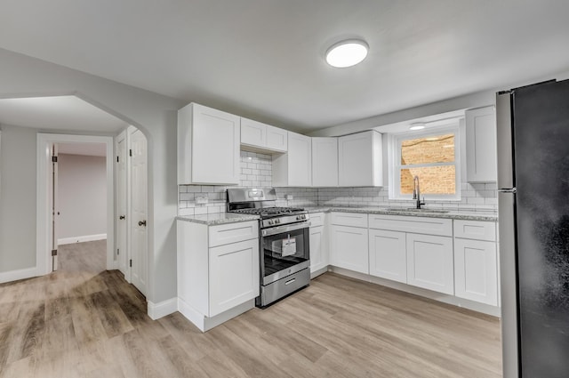 7133 W 16th St, Berwyn, IL 60402 - kitchen featuring stainless steel range with gas cooktop, freestanding refrigerator, a sink, light wood finished floors, and light stone counters
