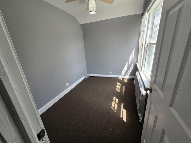 carpeted spare room featuring baseboards and ceiling fan