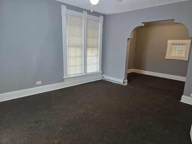 spare room with arched walkways, baseboards, ceiling fan, and dark carpet