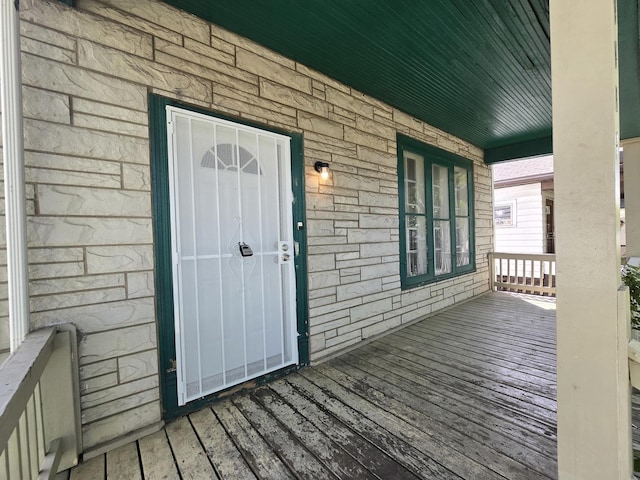 entrance to property with a porch and stone siding
