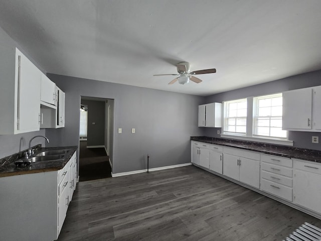 kitchen with a sink, ceiling fan, dark countertops, and white cabinets