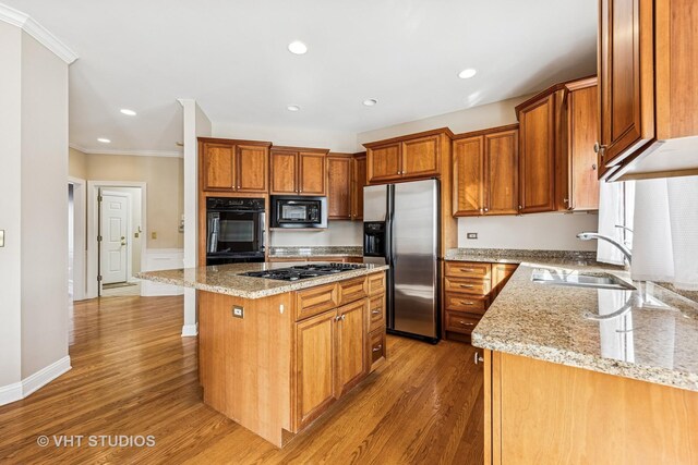 9310 Nicklaus Ln, Lakewood, IL 60014 - kitchen with black appliances, a sink, ornamental molding, light wood-style floors, and light stone counters