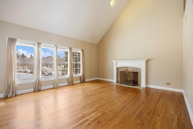 9310 Nicklaus Ln, Lakewood, IL 60014 - unfurnished living room featuring light wood-type flooring, a tiled fireplace, healthy amount of natural light, high vaulted ceiling, and baseboards